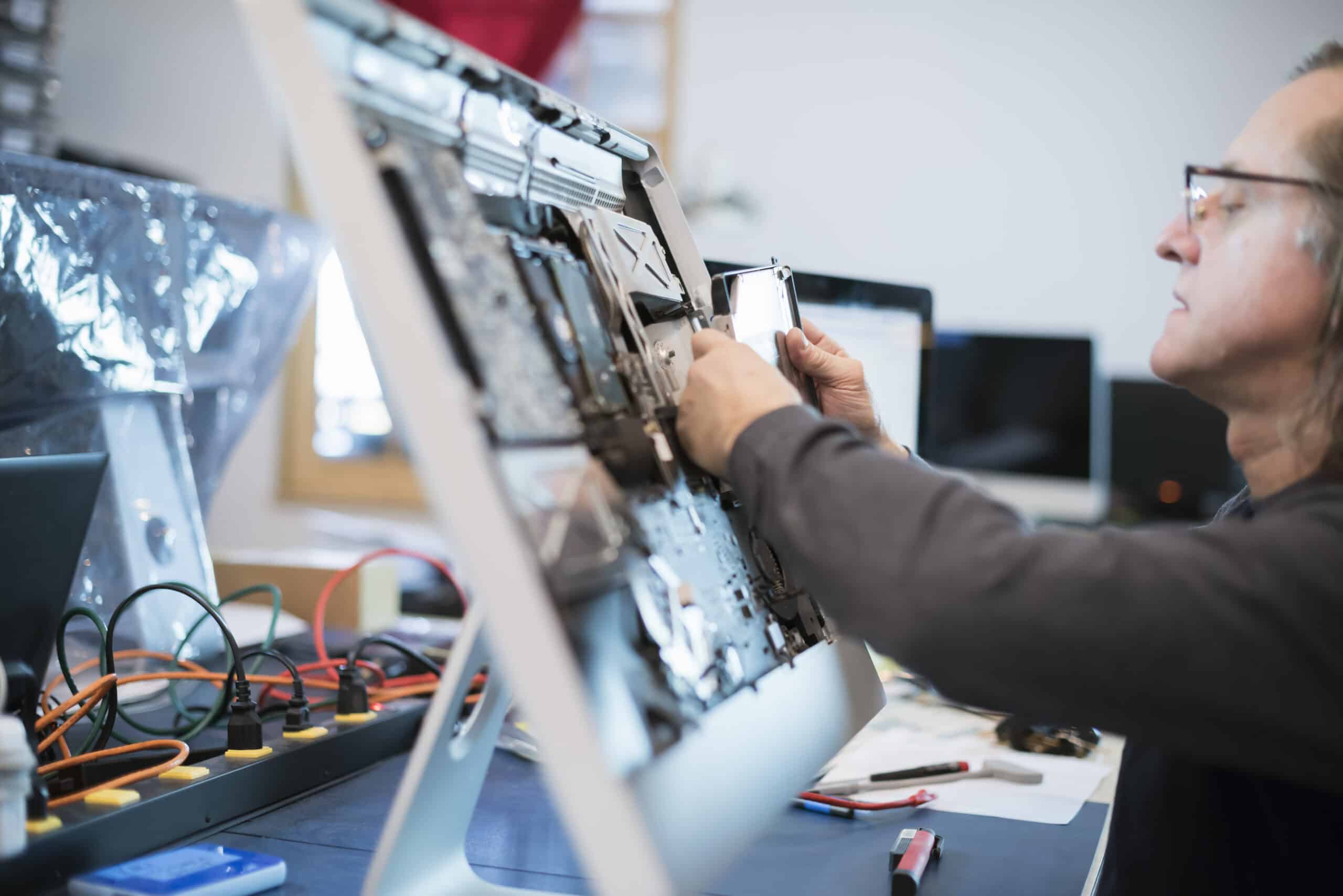 Computer Repair Shop,USA,Computer Repair Shop. A man with a computer monitor, taking it apart to mend it.