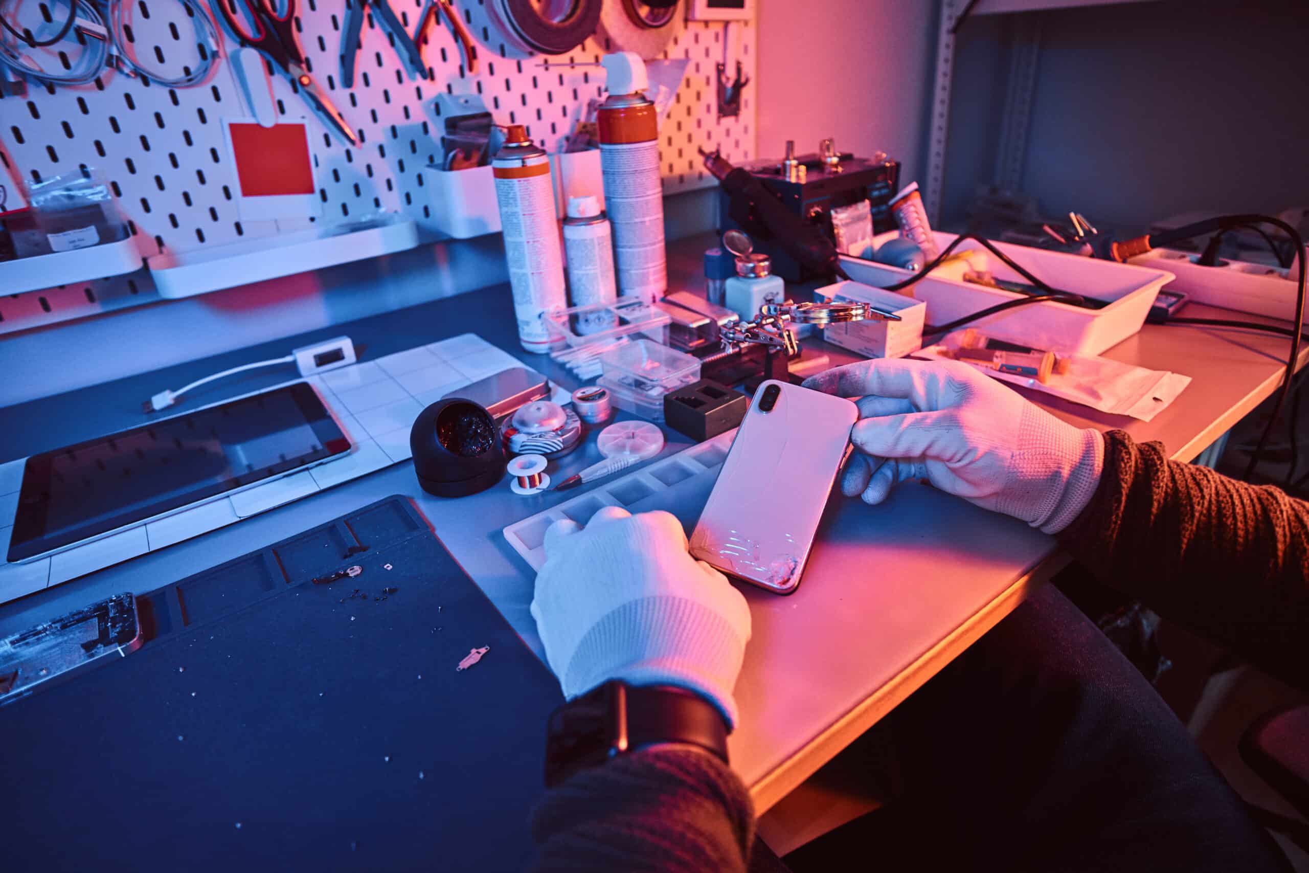Electronic technician holds a modern smartphone with a broken body