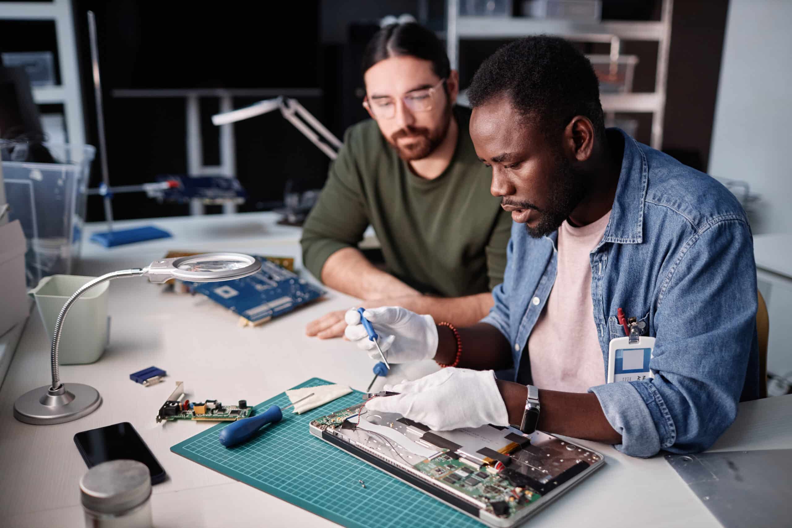 Two people fixing computer in tech repair